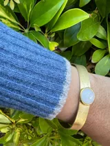 Pulsera rígida dorada con piedra circular blanca y pulsera rígida dorada con piedra circular roja.