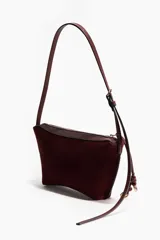 Cartera de hombro color borravino con acabado de textura suave, detalles en material sintético y cierre superior con tirador largo adornado con un nudo decorativo y argollas metálicas. Cuenta con una correa larga ajustable mediante hebilla.