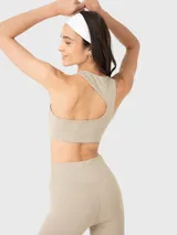 Conjunto deportivo de dos piezas compuesto por un top deportivo de escote redondo y calzas largas de tiro alto, ambos en color beige. El set destaca por su diseño minimalista y ajuste cómodo.