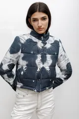Campera puffer corta con cuello alto, cierre frontal con botones a presión y estampado abstracto de puntos en tonos azul oscuro y blanco.