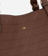 Cartera tipo hobo de gran tamaño en color marrón, confeccionada en poliuretano con textura geométrica grabada en relieve. Presenta doble asa de hombro con hebillas metálicas decorativas y cierre principal mediante botón.