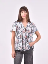 Blusa estampada con motivos de hojas en tonos gris claro, azul oscuro y rosado pálido. Presenta escote en V con lazo para atar, frunce bajo el busto y mangas cortas con volado.