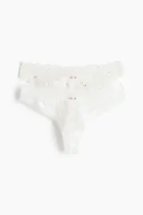 Pack de dos bombachas brasileras de encaje blanco con cintura baja, refuerzo forrado y corte alto en la parte trasera. Una de las bombachas tiene pequeños detalles bordados de flores rosadas.