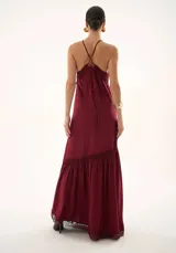 Vestido largo color bordó con cuello halter, detalle de encaje en la cintura y en el ruedo, y falda con volado inferior.