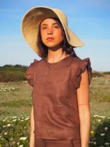 Blusa de lino color marfil, sin mangas, con detalles de volados en los hombros y cuello redondo.
