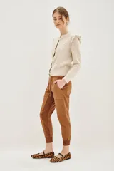 Pantalón tipo babucha de gabardina elastizada, color negro, con cintura elástica ajustable mediante cordón, puños en los tobillos, bolsillos diagonales frontales y bolsillos traseros con solapa y botón.