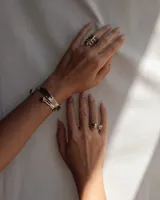 Brazalete rígido abierto de metal color plateado, con terminaciones en forma de herradura.