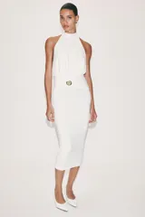 Vestido midi blanco de cuello halter, confeccionado con mezcla de poliamida. Presenta detalle de drapeado lateral con un broche metálico dorado en forma de caracola y cierre en la espalda ajustable con lazadas.