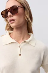 Sweater de punto color crudo, con cuello polo y cierre frontal de tres botones en tono carey. De manga larga y corte holgado.