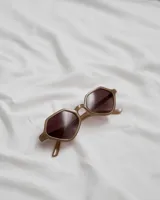 Lentes de sol color marrón claro con forma hexagonal y lentes marrones.