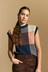 Chaleco tejido sin mangas con diseño de bloques a cuadros en tonos azul marino, salmón y beige. Presenta cuello redondo a la base y terminaciones acanaladas en contraste.