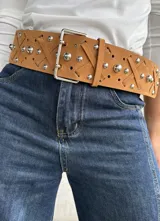 Faja ancha de gamuza color camel, con diseño de tiras entrecruzadas y tachas metálicas plateadas. Cuenta con una hebilla metálica rectangular plateada.