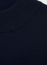 Vestido midi de punto fino color azul marino, con diseño recto y holgado. Presenta cuello perkins, manga larga con puños acanalados y aberturas laterales en el bajo.