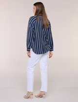 Camisa de crepe blanca con rayas verticales negras, cuello camisero, mangas largas raglán y cierre frontal con botones.