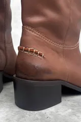 Botas de cuero vacuno color negro, de caña media con bordado a contratono, tacón bajo, punta alargada redondeada y suela cuadrada lisa.