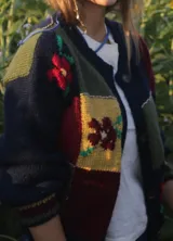 Saco tipo cardigan de tejido de punto con diseño patchwork multicolor, con bloques en tonos azul marino, rojo, amarillo y verde, decorado con motivos florales bordados. Presenta cuello en V, cierre frontal con botones y puños acanalados.