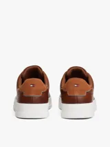 Zapatillas de estilo tenis Tommy Hilfiger confeccionadas en piel color marrón, con diseño de corte bajo, cordones al tono y suela de goma blanca. Presenta un panel de gamuza a contraste en el talón y el logo de la marca grabado en el lateral.