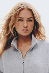 Campera corta de velour gris claro, de corte holgado, con cuello elevado, cierre frontal y bolsillos al bies. Presenta elástico fruncido en puños y bajo.