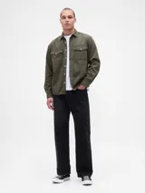 Camisa de jean de corte clásico en color azul oscuro, con cierre frontal de botones, cuello camisero y dos bolsillos frontales con solapa y botón.