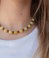 Collar corto de cuentas esféricas de cristal en tonos amarillo claro y borravino alternados.