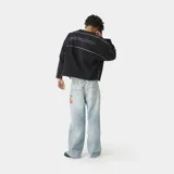 Buzo oversize de algodón color negro con cuello redondo. Presenta el logo de la marca bordado en el frente, líneas blancas en contraste a lo largo de las mangas y terminaciones con bordes deshilachados.