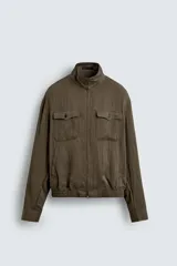 Cazadora de hombre color verde oliva, estilo bomber o Harrington, con cuello subido, cierre frontal de cremallera y puños y bajo elásticos. Presenta bolsillos de plastrón con solapa en el pecho y bolsillos de vivo en la cadera.