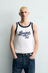 Camiseta sin mangas slim fit color blanco, con cuello redondo y sisas ribeteadas en azul marino. Estampado frontal con la palabra "League" y el número "'86" en azul marino.