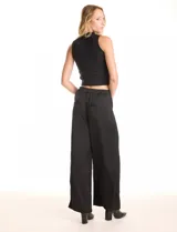 Pantalón palazzo de tiro alto confeccionado en tela satinada. Presenta una pretina delantera con pasadores, cierre y broche, mientras que la parte trasera cuenta con elástico para mayor comodidad. Incluye bolsillos verticales en el frente.