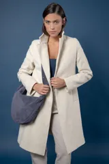 Tapado de corte sastre con diseño de espiga en tonos blanco y negro. Cuenta con solapas clásicas, cierre frontal de un botón y bolsillos laterales.