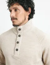 Sweater de punto color azul marino, con cuello alto, cierre frontal parcial y tapeta con botones. Presenta mangas raglán y puños y ruedo acanalados.