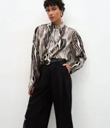 Pantalón de sastrería negro, modelo cropped de corte recto y tiro alto. Presenta pinzas frontales, bolsillos traseros y se incluye un cinturón de cuero sintético con hebilla metálica.