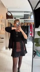 Minifalda de gabardina elastizada combinada en color negro y marrón, con detalles de tachas metálicas en las costuras verticales y en el borde inferior de la falda, y diseño con vuelo en el ruedo.