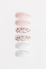 Pack de seis broches para el pelo tipo tic-tac, forrados en tela con diferentes diseños: dos lisos en color rosado, dos con estampado floral y dos blancos con bordado de flores.
