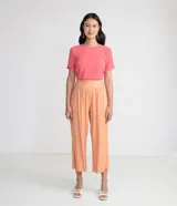 Blusa blanca de poliéster con cuello redondo, mangas cortas, cierre trasero en forma de gota, pequeñas aberturas laterales y acabados en pespuntes en las mangas y el cuello.