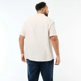 Camisa de lino mezclado de manga corta en color beige, con cuello mao y cierre frontal con botones.