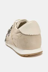 Zapatillas deportivas color beige con pespuntes en el cuerpo, parte trasera en contraste de color y cierre mediante cordones. La altura de la suela es de 2 cm.