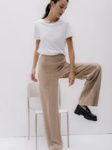 Pantalón de vestir color beige, de corte recto y pierna ancha, con detalle de pinzas al frente.