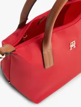 Cartera tote Tommy Hilfiger de nailon rojo, con dos asas superiores en tono tostado y una correa de mano o hombro tejida extraíble. Cuenta con cierre de cremallera superior, compartimento principal e insignia metálica con el monograma TH en el frente.