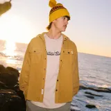 Camisa tipo overshirt de pana color mostaza, con cierre frontal de botones metálicos, dos bolsillos frontales con solapa y manga larga con puños abotonados.