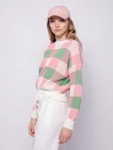 Sweater de tejido de punto con diseño jaquard a cuadros en tonos rosa y verde. Es de manga larga y cuello a la base.