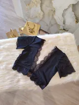 Top de encaje y lycra color negro, con escote profundo en V adornado con puntilla, mangas cortas de encaje y diseño con transparencias de microtul en los laterales y espalda.