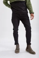 Pantalón de jean corte slim fit en color negro lavado, con cierre de botón y cremallera, y bolsillos laterales y traseros.