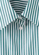 Camisa de popelín de algodón orgánico con diseño oversize, cuello camisero, manga larga con puños abotonados y cierre frontal de botones.