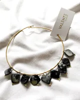 Gargantilla dorada con piedras cuadradas nacaradas en tonos grises y negros.