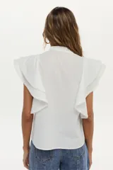 Blusa blanca sin mangas, con volados amplios en los hombros, bordado a tono en el pecho, detalles de tablones a lo largo del cuerpo y cuello elevado con volados.