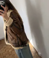 Campera gamulán de efecto cuero marrón con interior y detalles de corderito sintético en cuello, solapas, puños y dobladillo. Posee bolsillos laterales y tiras ajustables con hebilla en los laterales de la cintura.