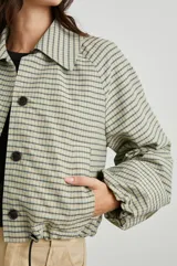 Campera corta a cuadros color verde, con cuello camisero, cierre con botones, bolsillos y cordón ajustable en el ruedo.