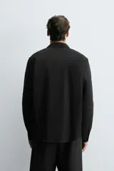 Camisa blanca de manga larga con cuello italiano y cierre frontal de botonadura. Corte regular fit.