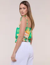 Top crop de rayón con estampado floral tropical en tonos verdes, amarillos y blancos. Presenta escote recto, frunces elastizados en el pecho y la cintura, y tirantes finos para anudar en los hombros.