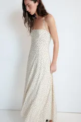 Vestido largo de color negro con cuello halter y escote recto. Presenta un diseño fluido con cierre de cremallera oculta en la espalda y lazada ajustable en el cuello.